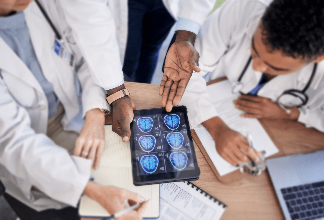 A group of doctors reviewing patient data and using the consistent interpretation of results provided by health assessment software to more effectively provide medicals at scale.